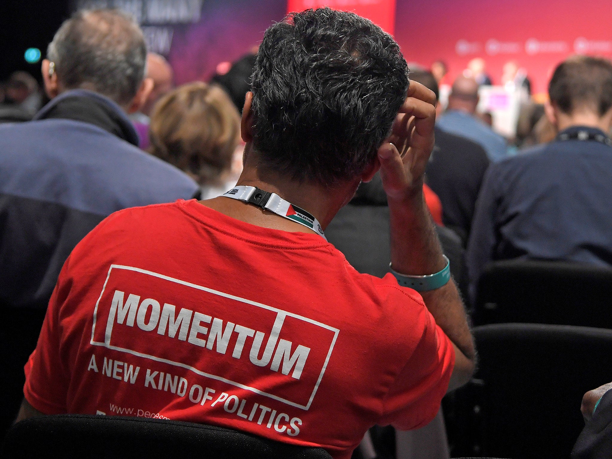 A member of the audience wearing a Momentum T-shirt listens to speeches at a Labour Party Conference