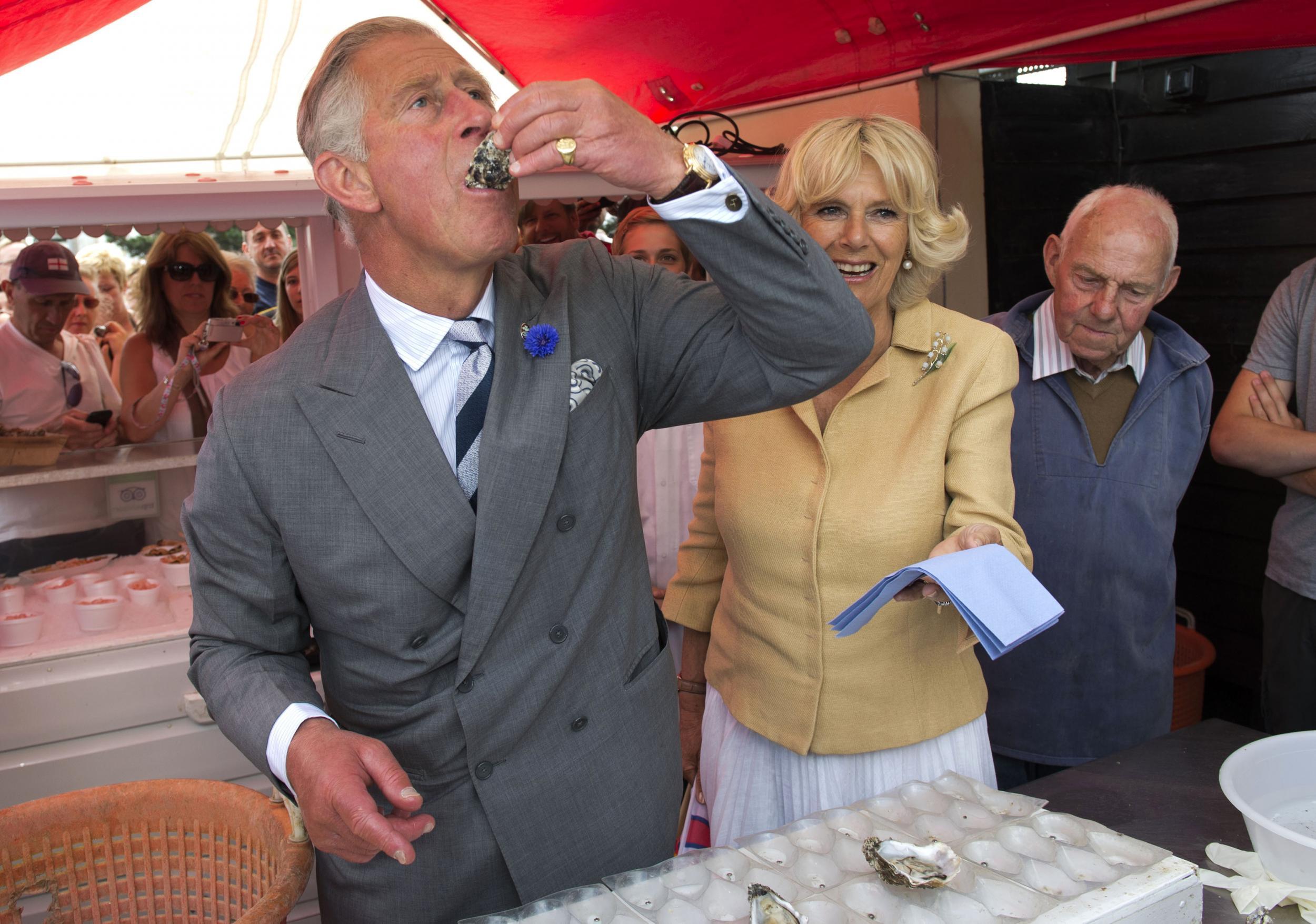 Prince Charles samples an oyster as Camilla, the Duchess of Cornwall, looks on during a visit to the Whistable Oyster Festival in Whistable on July 29 2013