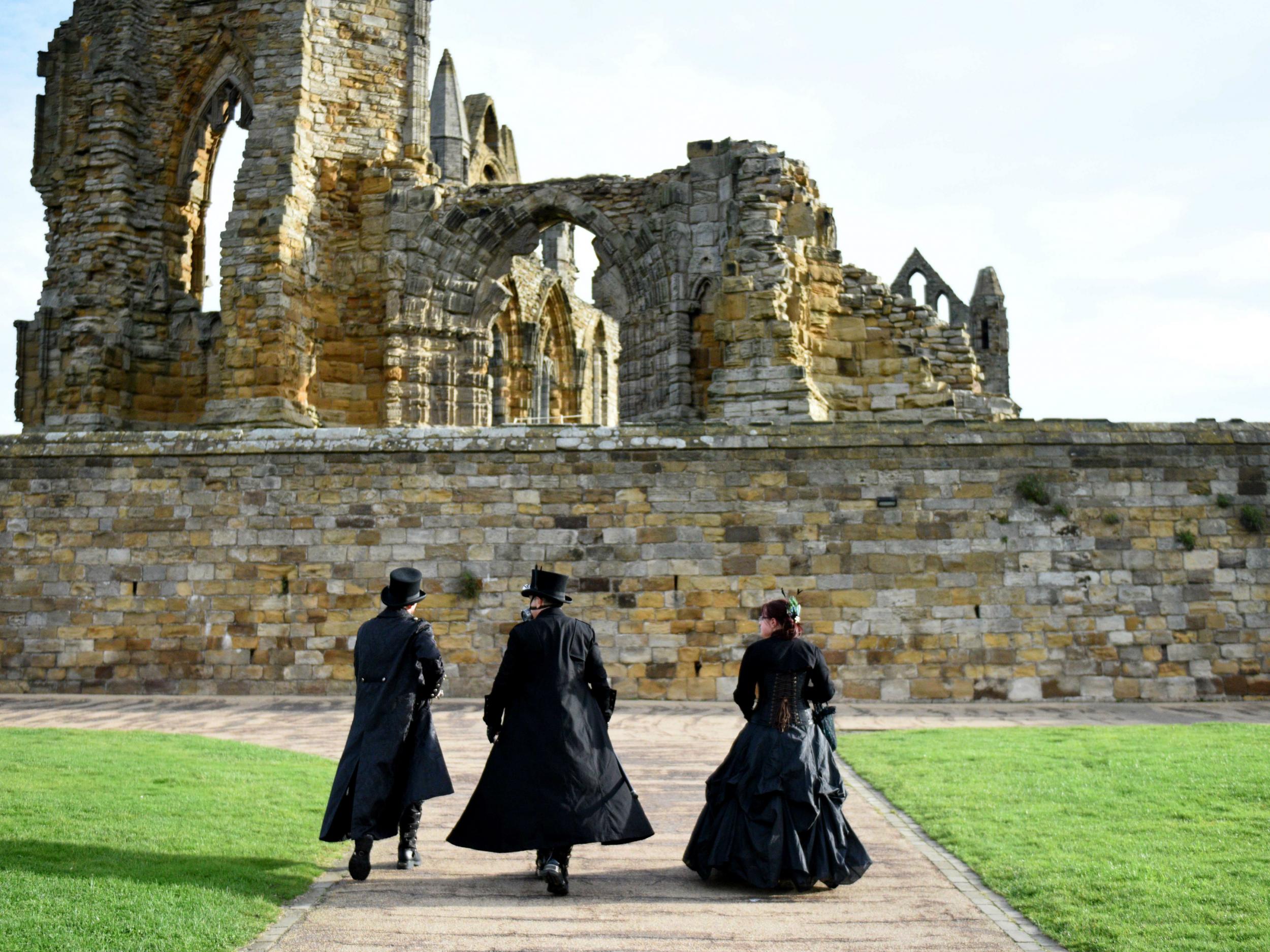 Participants dressed in gothic costumes walk near Whitby Abbey at the biannual 'Whitby Goth Weekend'