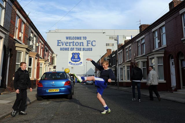Two children knock a ball about in the shadow of Goodison Park