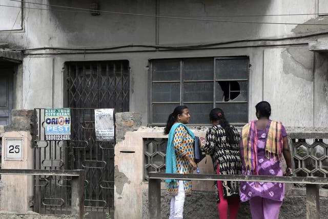 Women stand outside the house in India where 46-year-old Subhabrata Majumdar kept his mother's body in a freezer for three years
