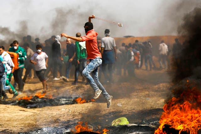 A Palestinian demonstrator uses a slingshot to throw stones during clashes with Israeli security forces