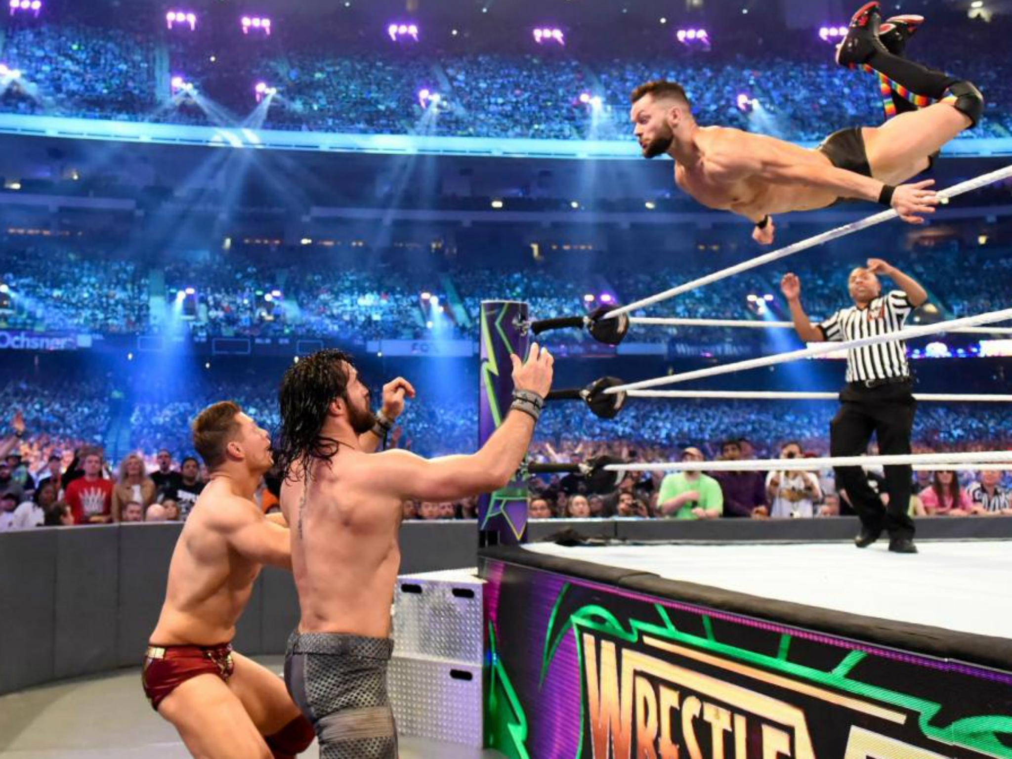 Finn Balor?soars over the top rope to splash onto Rollins and The Miz