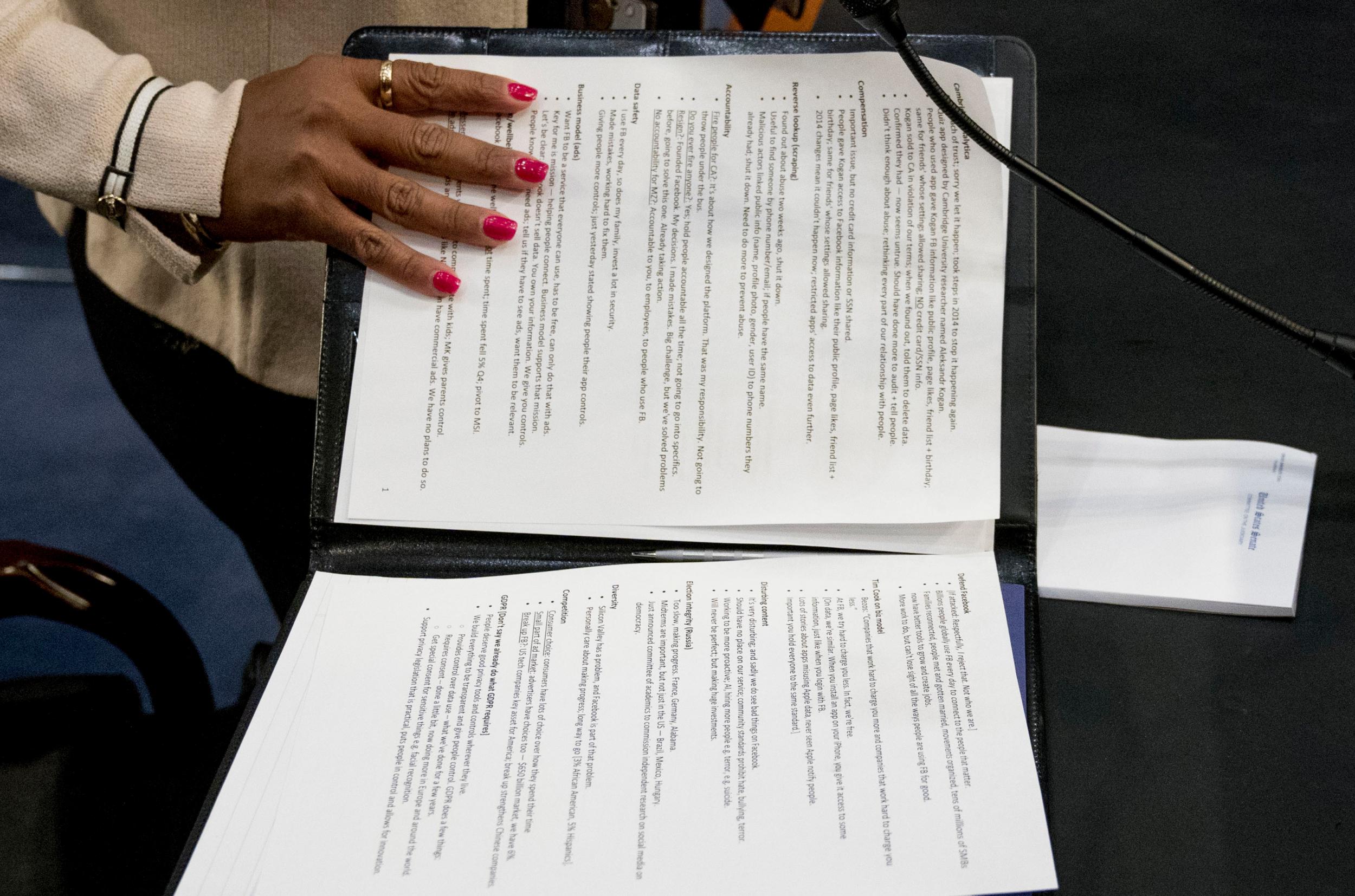 An aide to Facebook CEO Mark Zuckerberg closes a binder of notes left on the table as Zuckerberg takes a short break from testifying before a joint hearing of the Commerce and Judiciary Committees on Capitol Hill in Washington, Tuesday, April 10, 2018