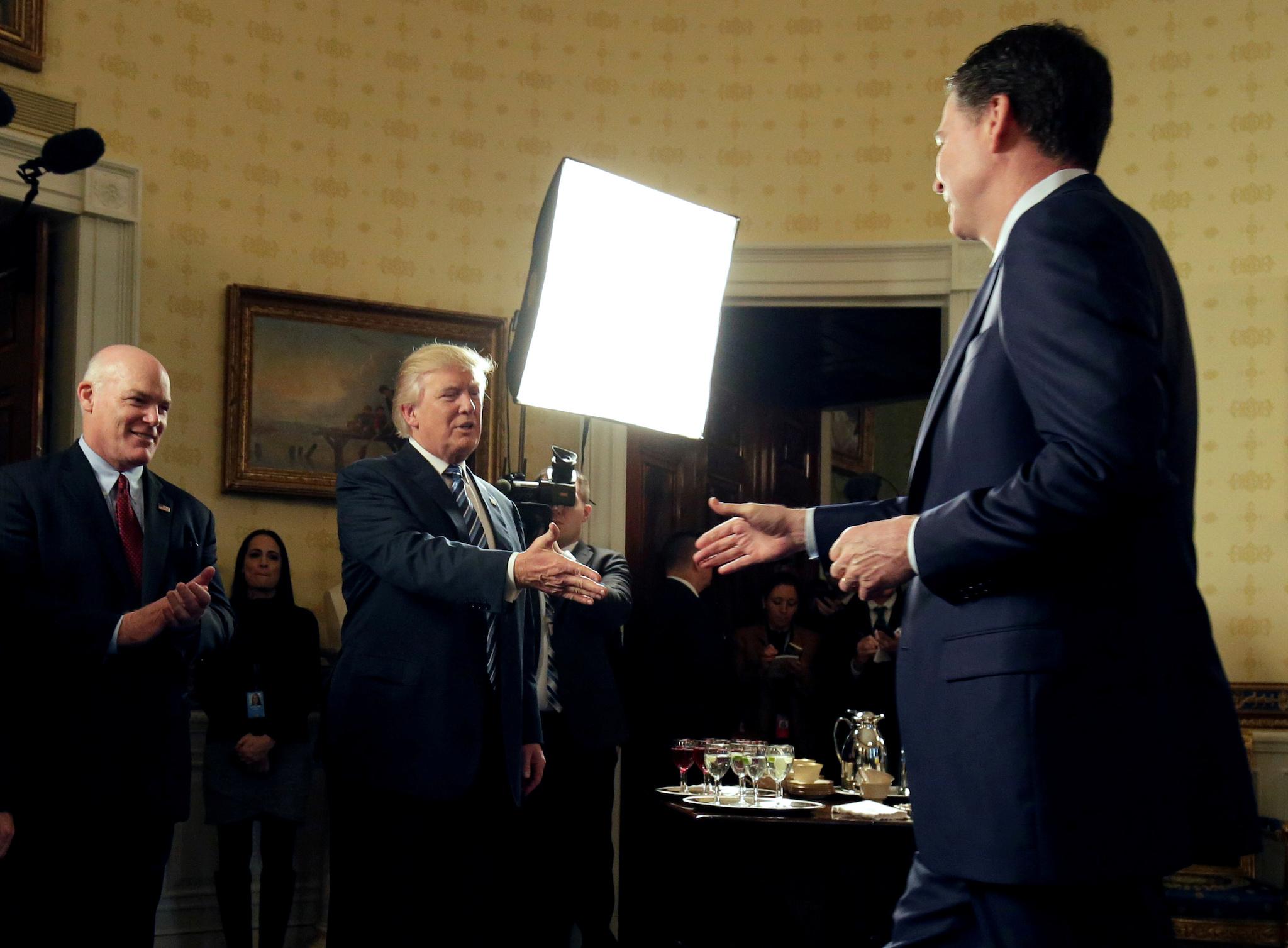 U.S. President Donald Trump greets Director of the FBI James Comey as Director of the Secret Service Joseph Clancy (L), watches during the Inaugural Law Enforcement Officers and First Responders Reception in the Blue Room of the White House