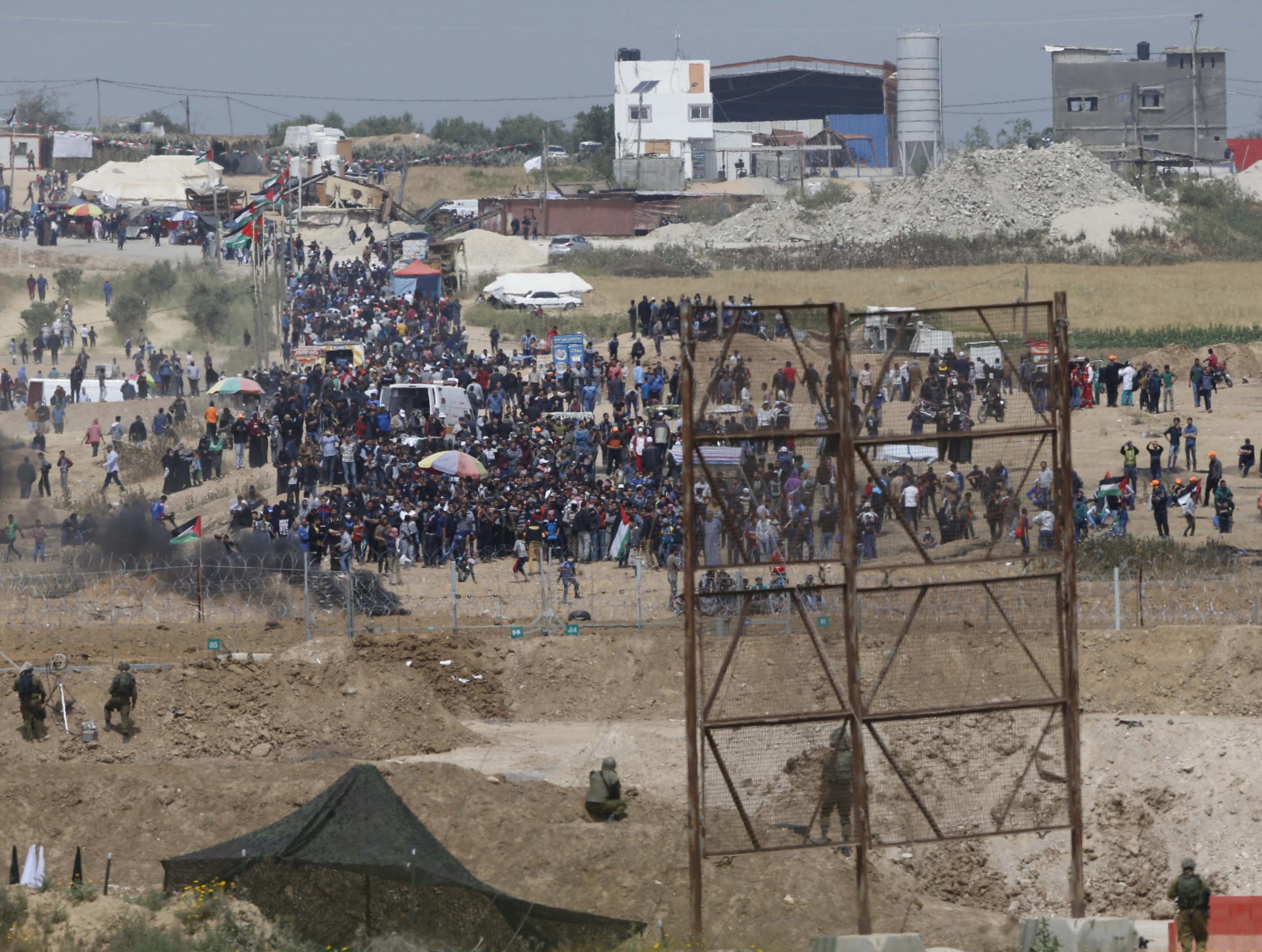 Israeli soldiers are seen as Palestinian demonstrators protest at the Israel Gaza border (AP Photo/Ariel Schalit)