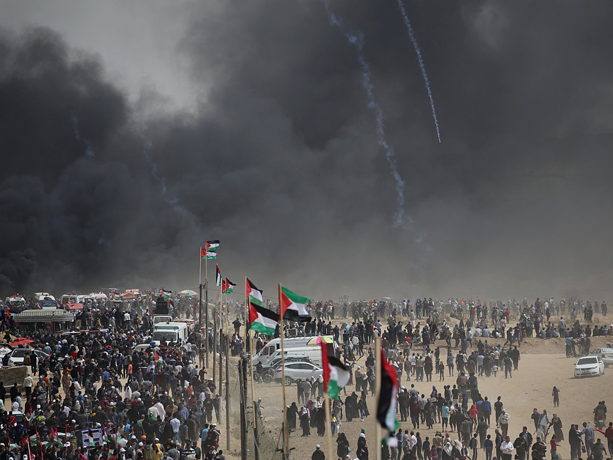 Palestinian protesters march amid black smoke of burning tiers during clashes with Israeli troops near the border