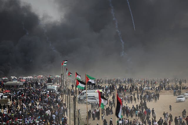 Palestinian protesters march amid black smoke of burning tiers during clashes with Israeli troops near the border