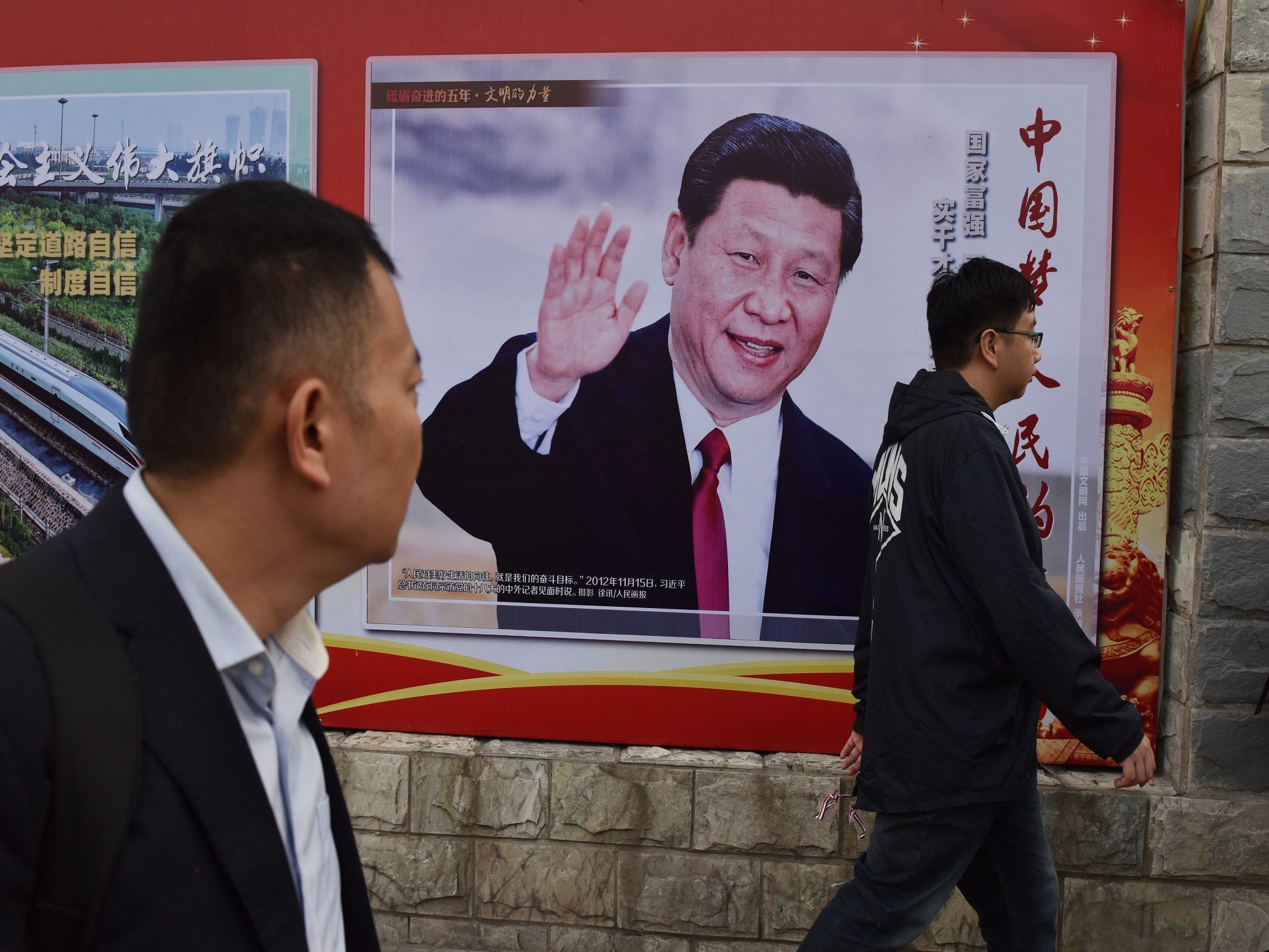 People walk past a poster featuring Chinese President Xi Jinping in Beijing