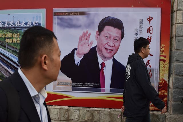People walk past a poster featuring Chinese President Xi Jinping in Beijing
