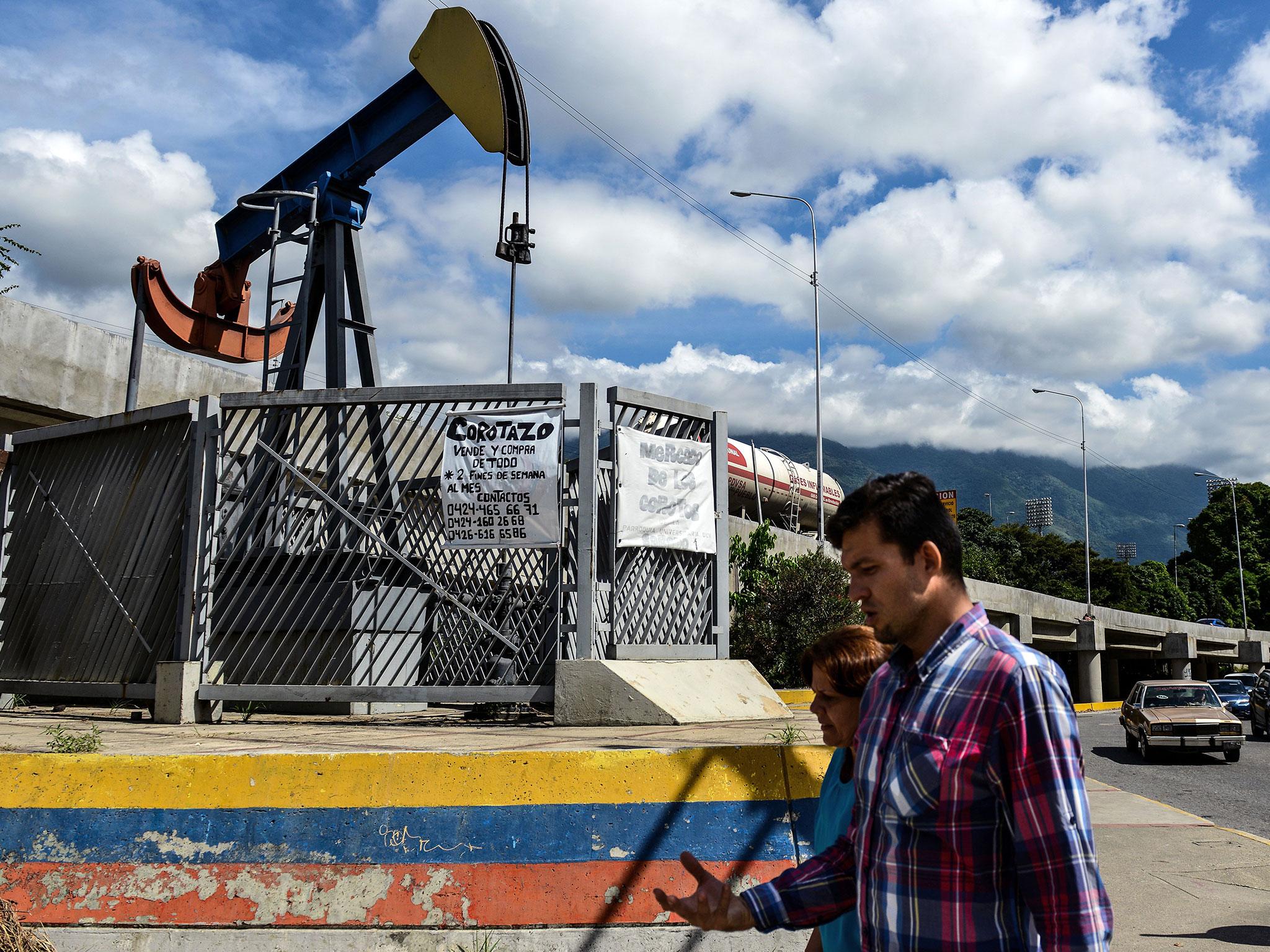 People walk by a small square with an oil pump in one of the access roads to the Central University of Venezuela, Caracas