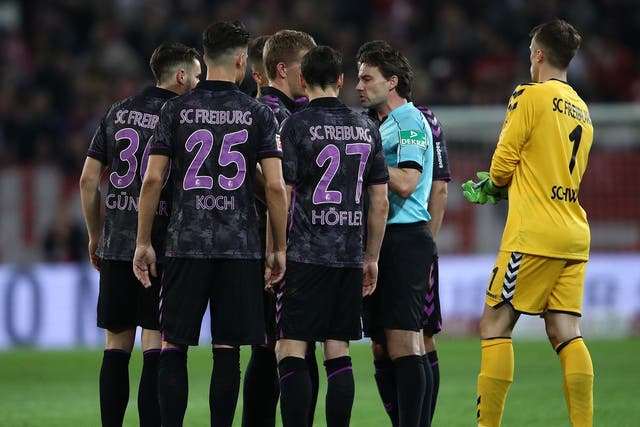 Referee Guido Winkmann is confronted after ordering the players back onto the pitch