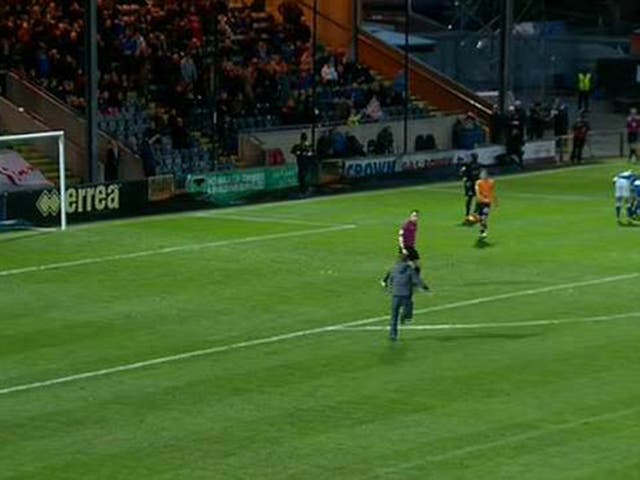 An Oldham supporter runs onto the pitch to confront referee Peter Bankes