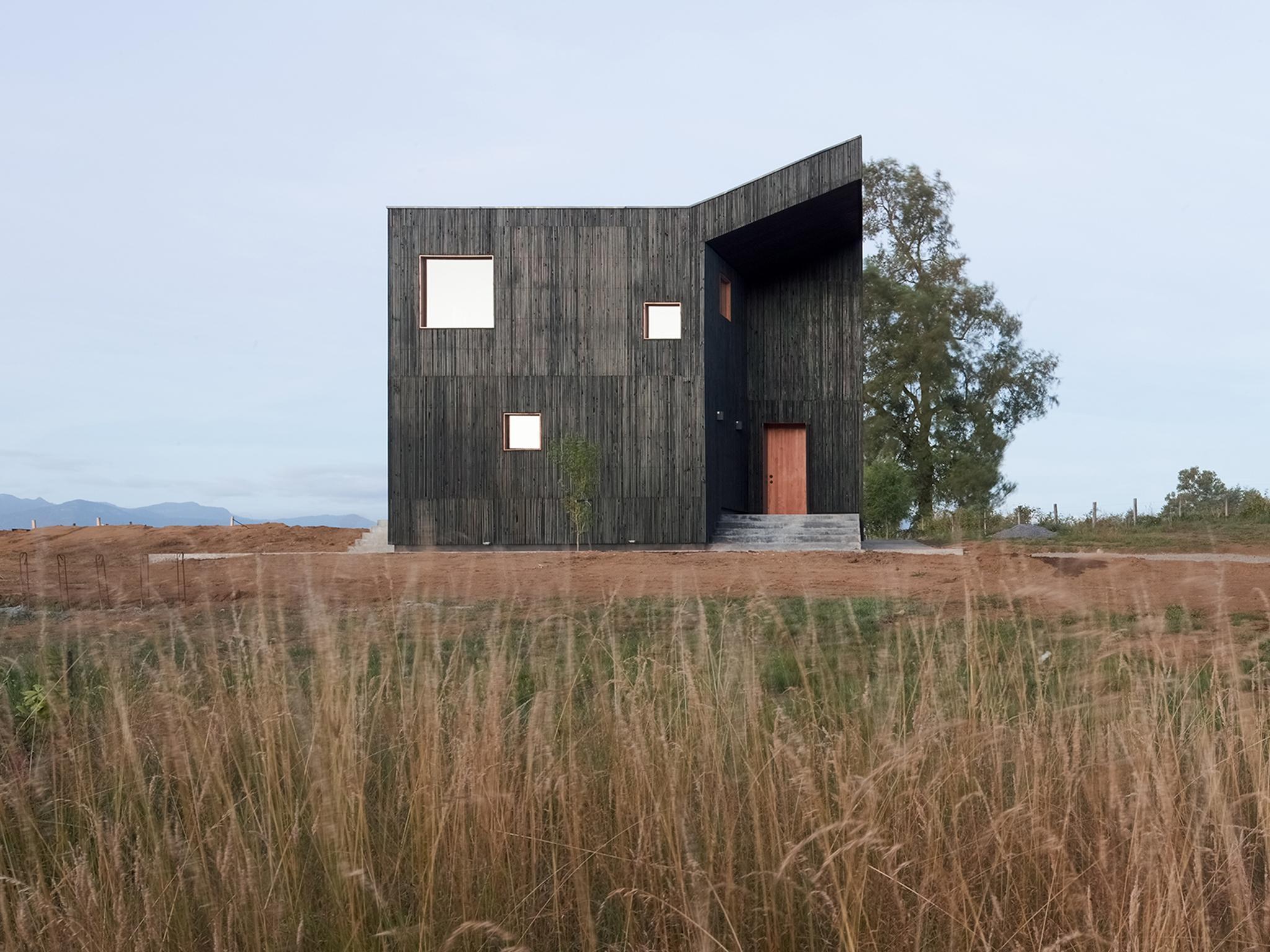 The home takes inspiration from local volcanic sand for the charcoal colour of the external timber panels