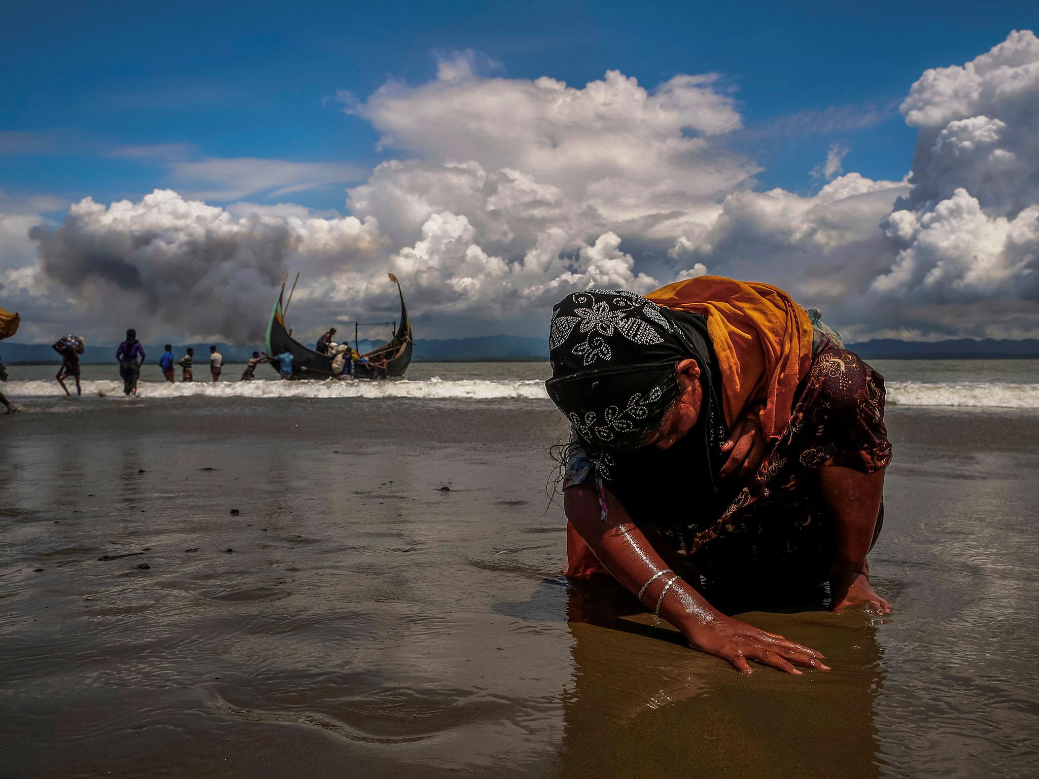 A refugee touches the shore after crossing the Bangladesh-Myanmar border by boat
