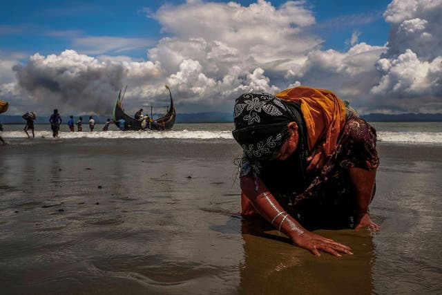 A refugee touches the shore after crossing the Bangladesh-Myanmar border by boat 