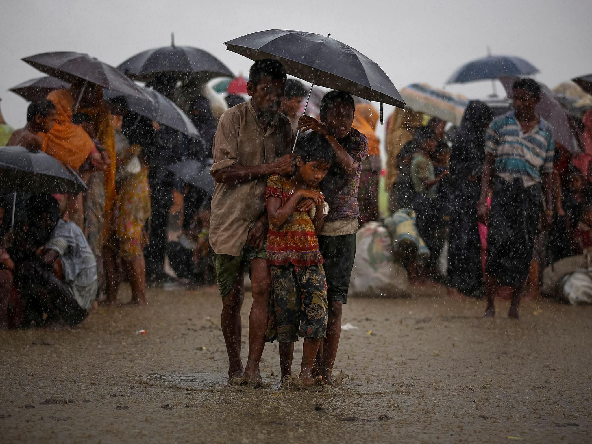 Rohingya refugees try to take shelter from torrential rain as they are held by the Border Guard Bangladesh (BGB) after illegally crossing the border, in Teknaf, Bangladesh