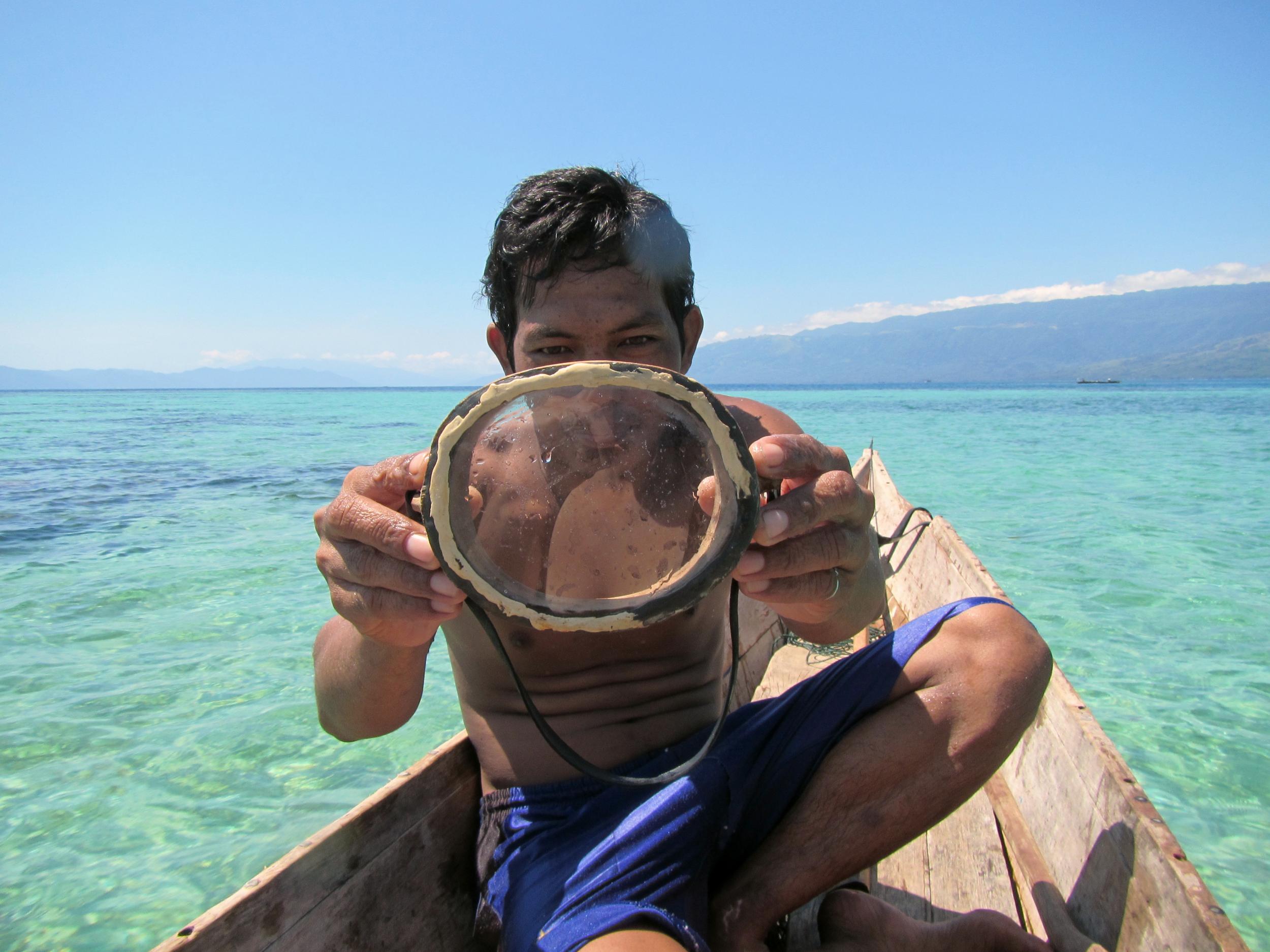 A Bajau diver displays a traditional wooden diving mask
