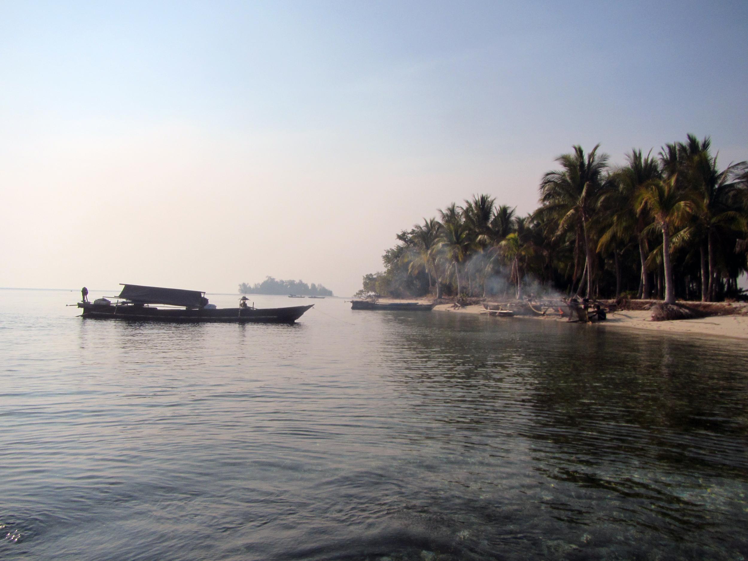 A small, unnamed island serves as a haven for visiting Bajau houseboats