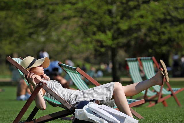 A woman lounges in the sunshine in a deckchair in St James Park