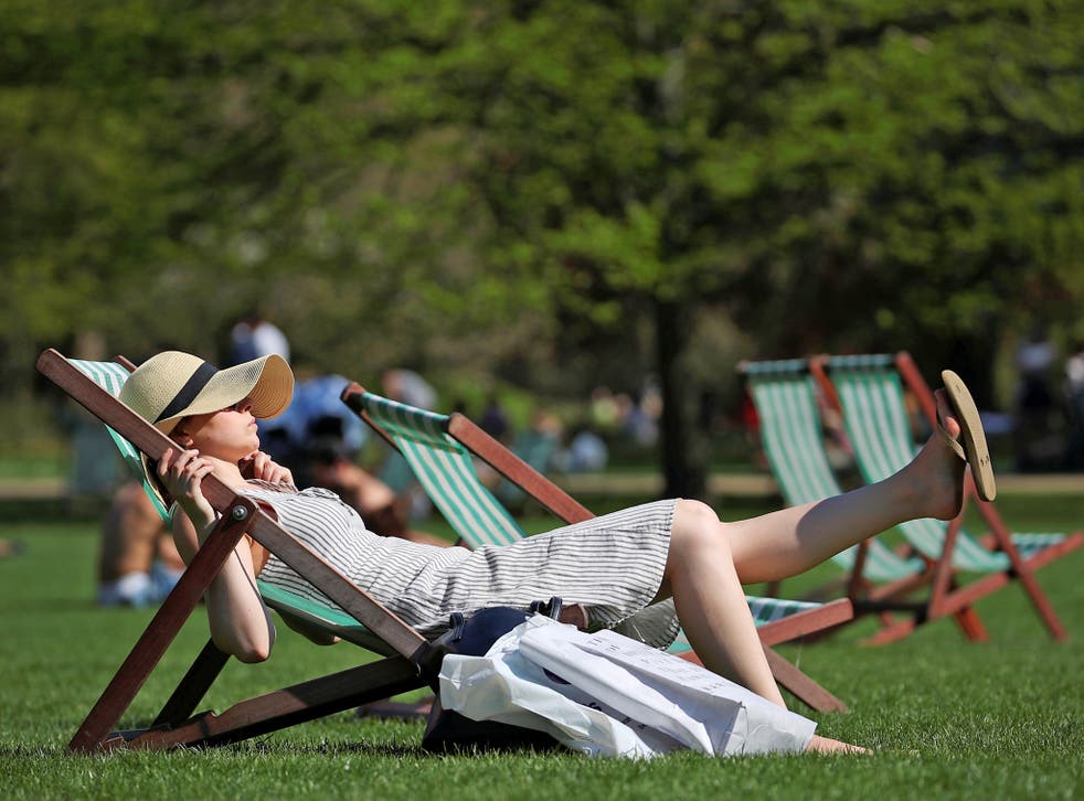 A woman lounges in the sunshine in a deckchair in St James Park