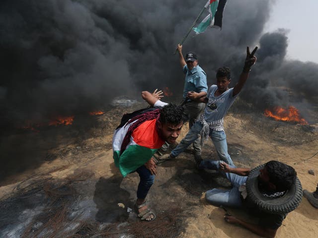 Demonstrators take cover from gunfire during protests on the Israel-Gaza border