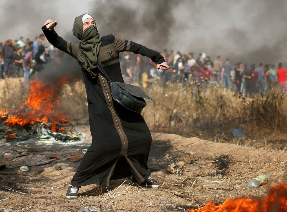 A girl hurls stones during clashes with Israeli troops at a protest where Palestinians demand the right to return to their homeland, at the Israel-Gaza border