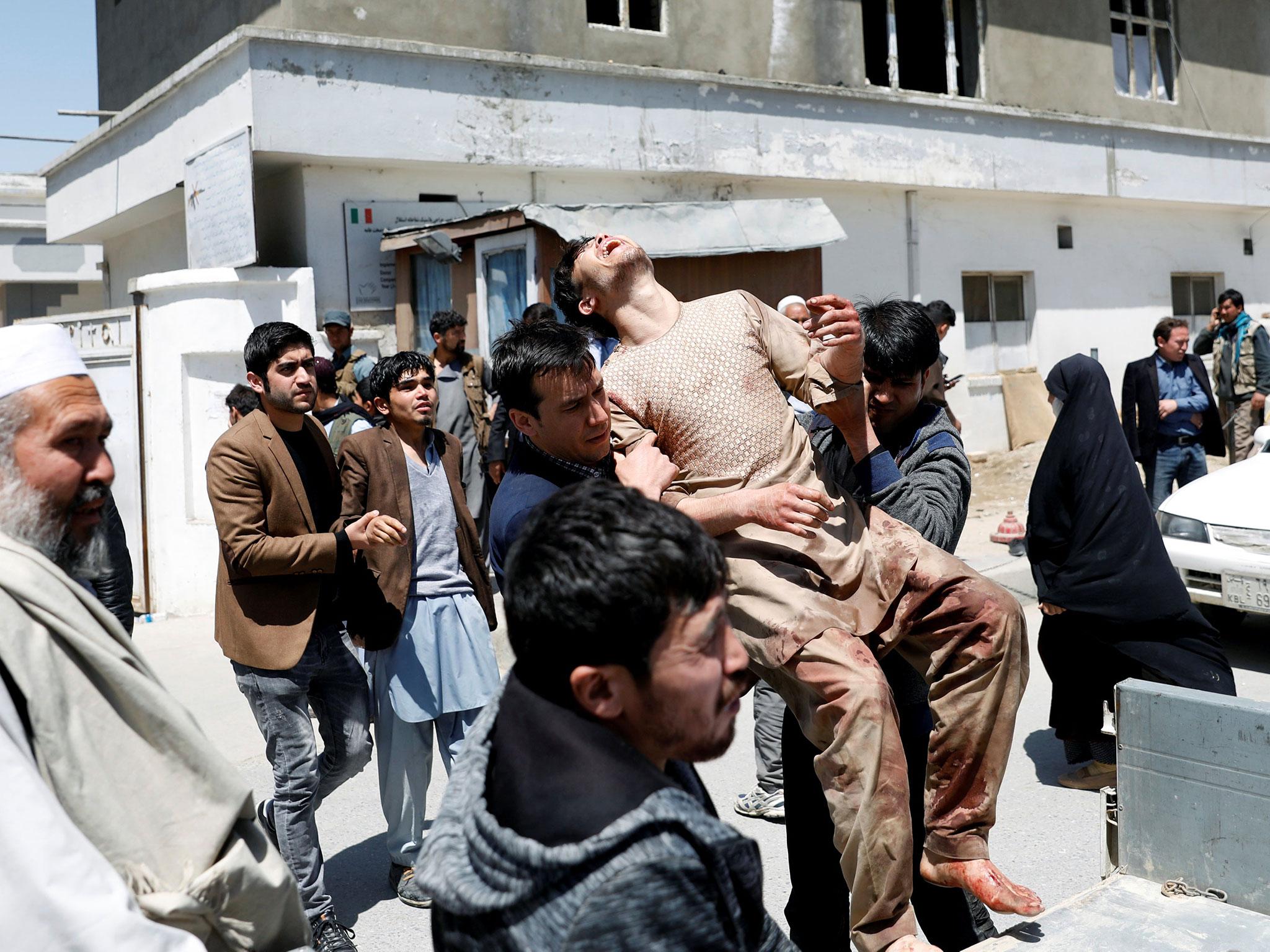 Relatives of the victims carry an injured man outside a hospital after a suicide attack in Kabul