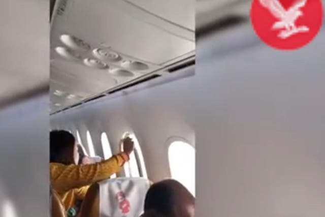 A flight attendant tries to fix a damaged window on an Air India flight between Amritsar and Delhi