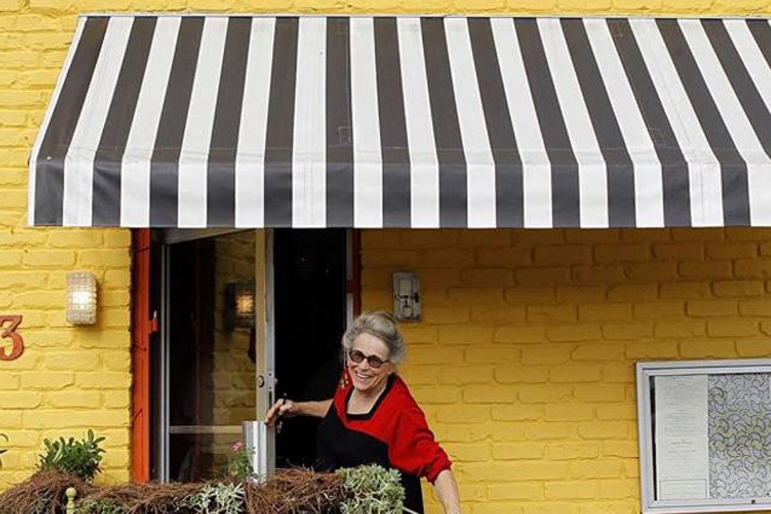 With her uniform of red dress, round glasses and Girl Scout pin, she's been the hostess of the restaurant since it first opened