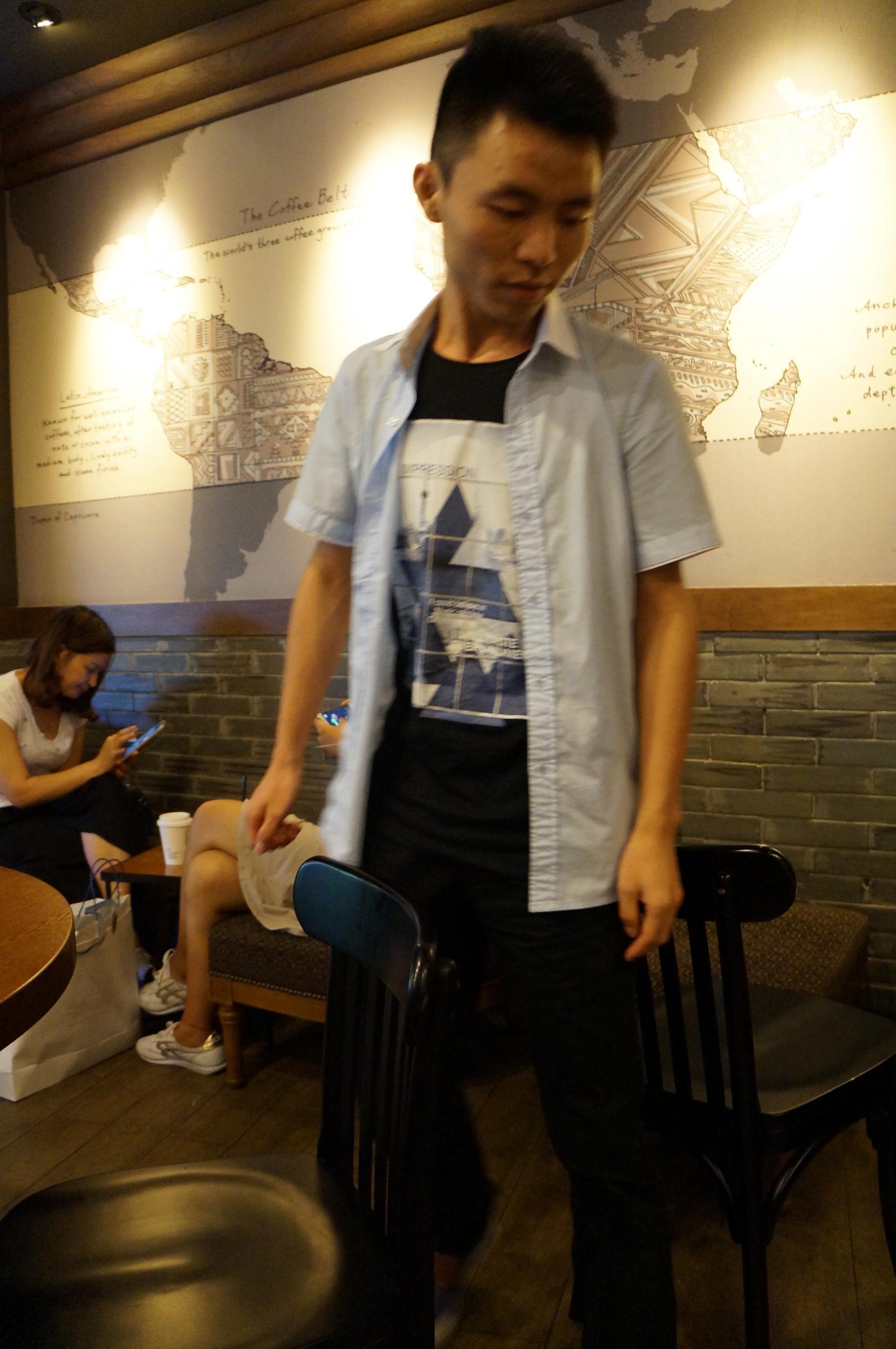 A research assistant demonstrates squeezing through the chair trap in a Shanghai Starbucks.