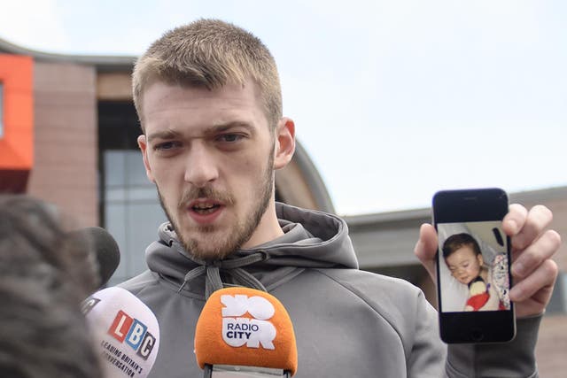 Tom Evans holds a photo of his son as he speaks to reporters outside Alder Hey hospital