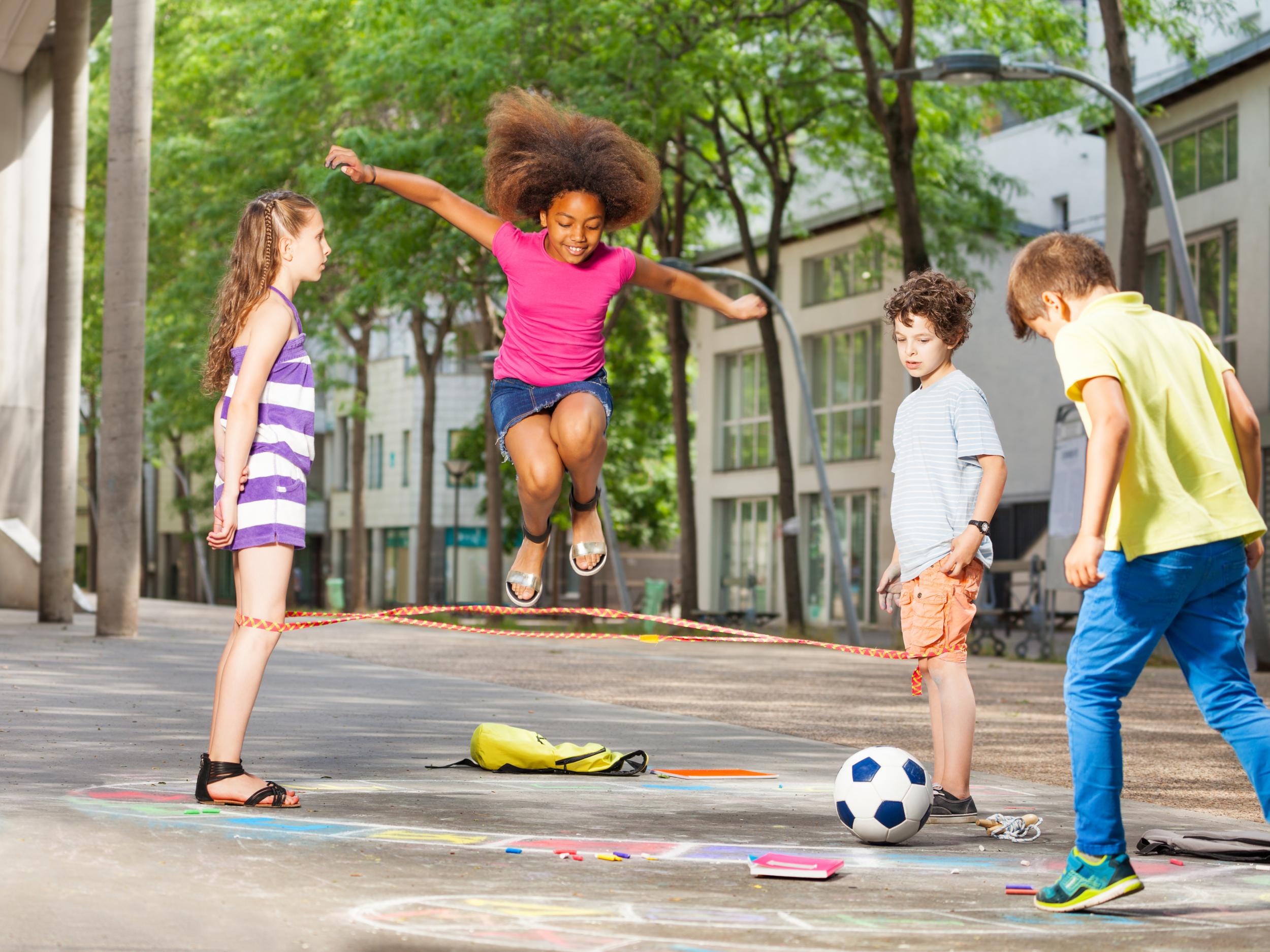 Children Playing On Playground In City Park Engaged In Football