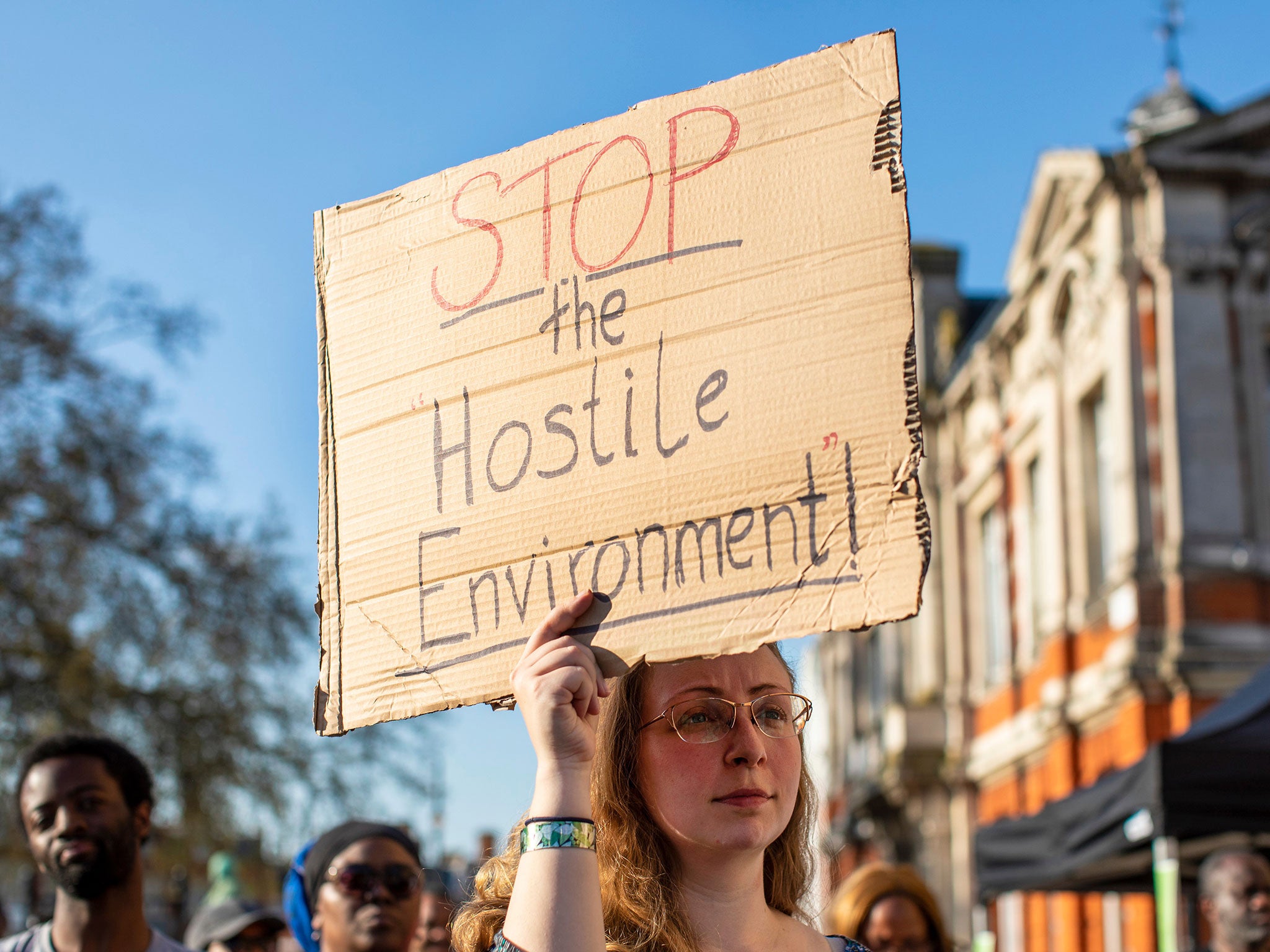 Protesters hold placards about the government's 'hostile environment' in Brixton
