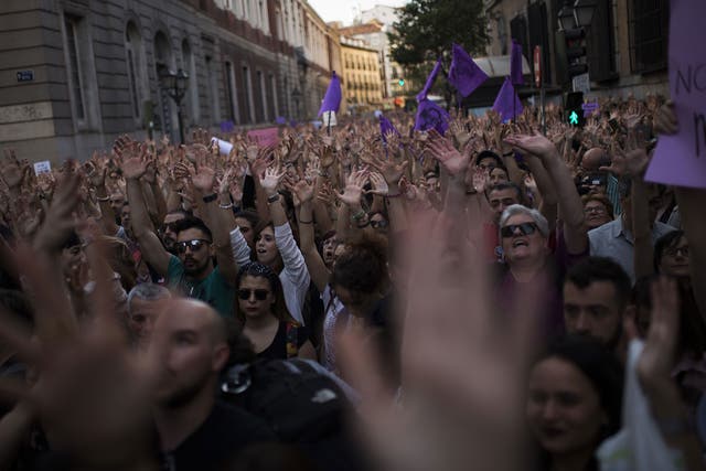 People lift their arms as they shout slogans during a protest outside the Justice Ministry in Madrid