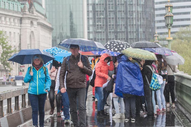 Pedestrians shelter form the rain on Westminster Bridge, London, on Friday