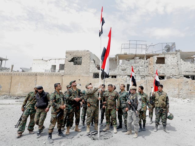 Syrian soldiers raise the national flag at al-Jourah neighborhood after it was recaptured from Isis militants in the south of Damascus, on 29 April 2018