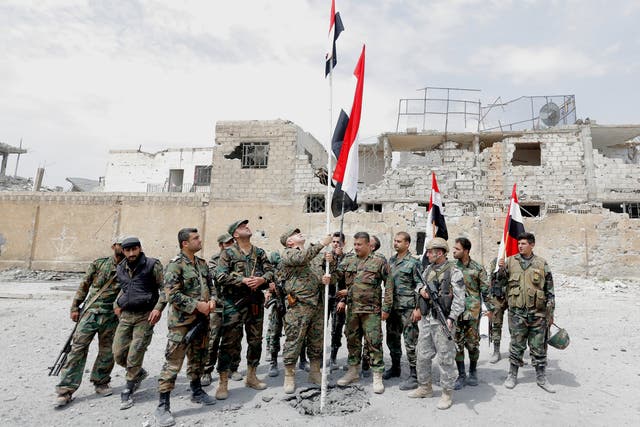 Syrian soldiers raise the national flag at al-Jourah neighborhood after it was recaptured from Isis militants in the south of Damascus, on 29 April 2018