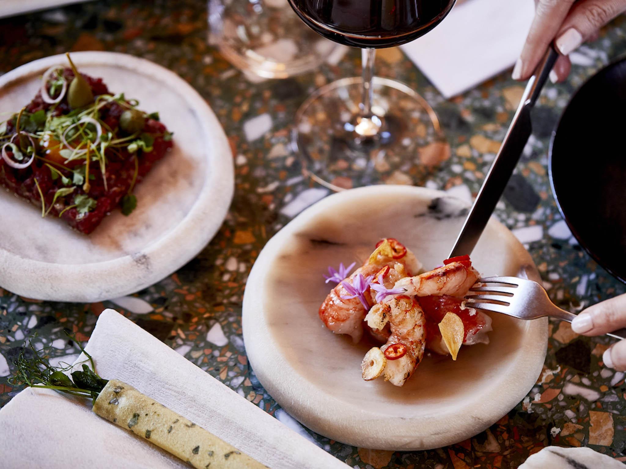 Small dishes are designed to share, and handmade stone plates contrast the beautiful terrazzo table tops