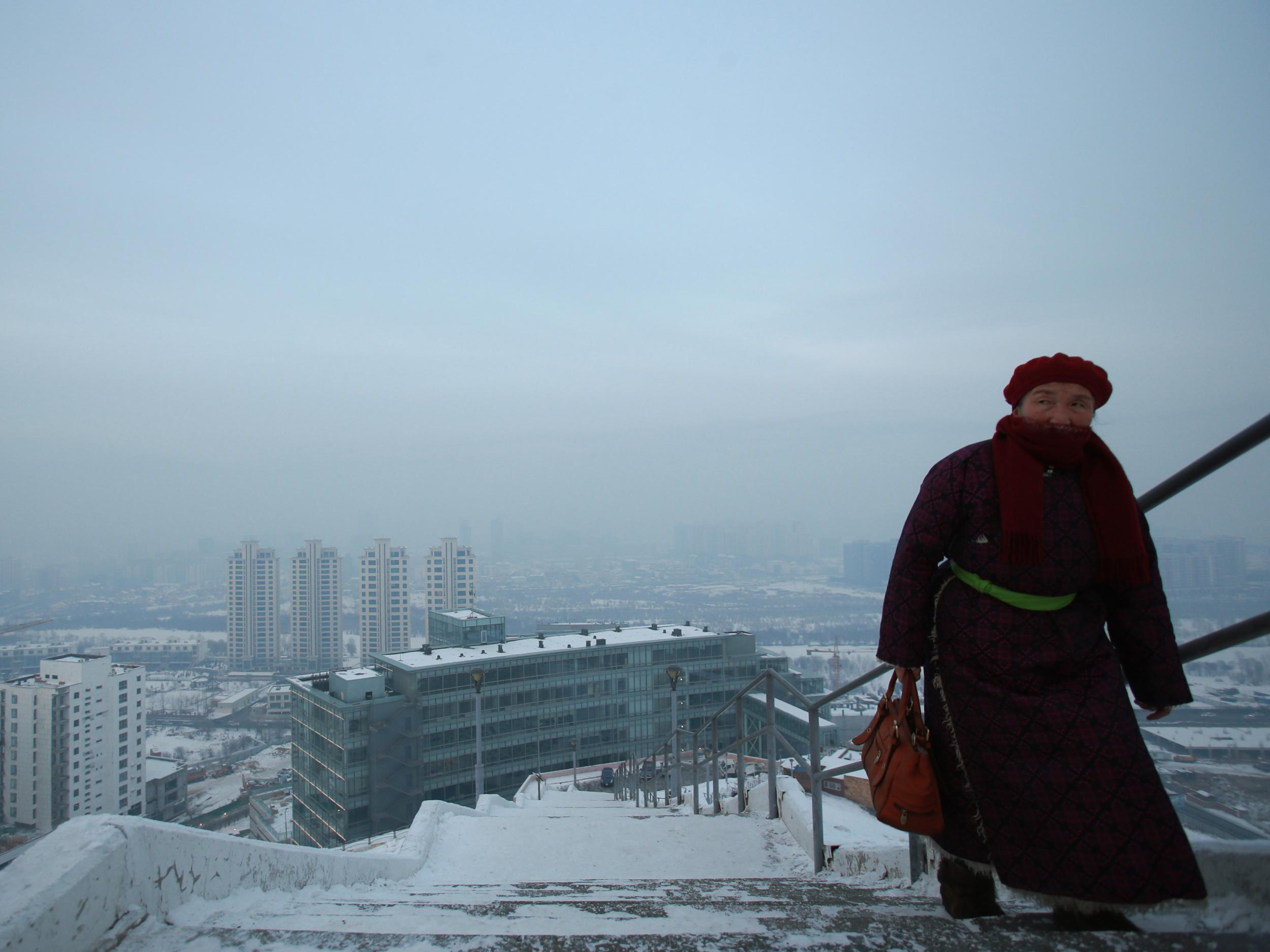 A resident walking up a set of stairs on a smog polluted day in Ulaanbaatar, the capital of Mongolia
