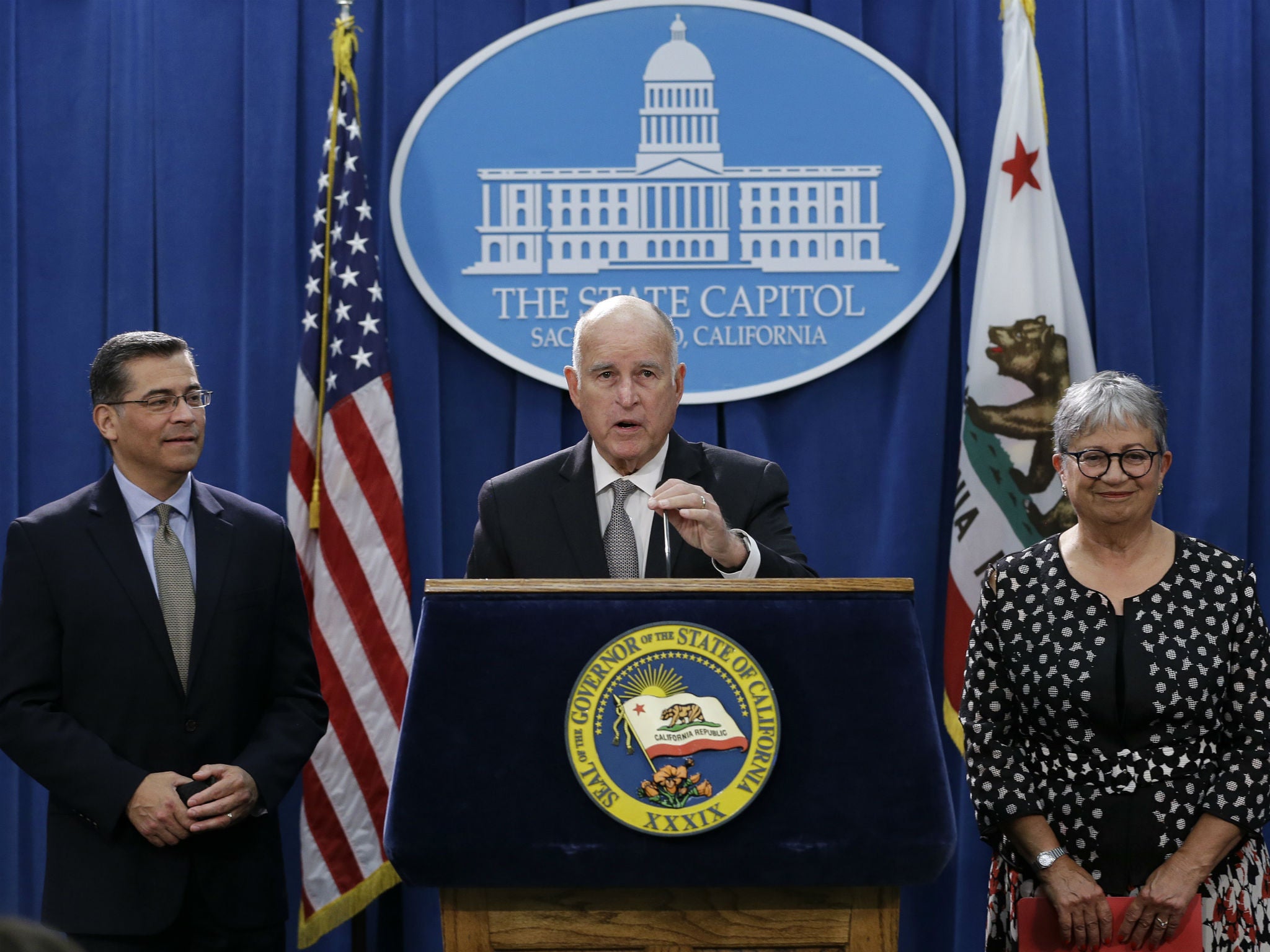 Jerry Brown, flanked by California Attorney General Xavier Becerra California Air Resources Board Chair Mary Nichols, discusses the lawsuit in Sacramento, California