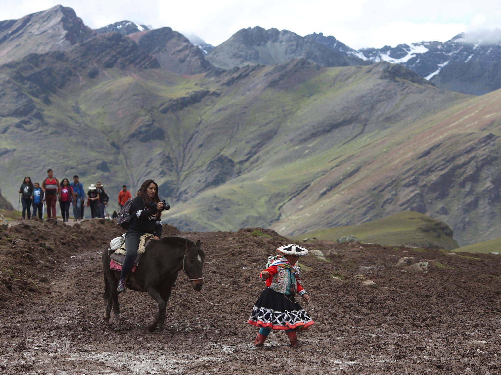 A local woman guides a tourist up to the mountain peak on horseback