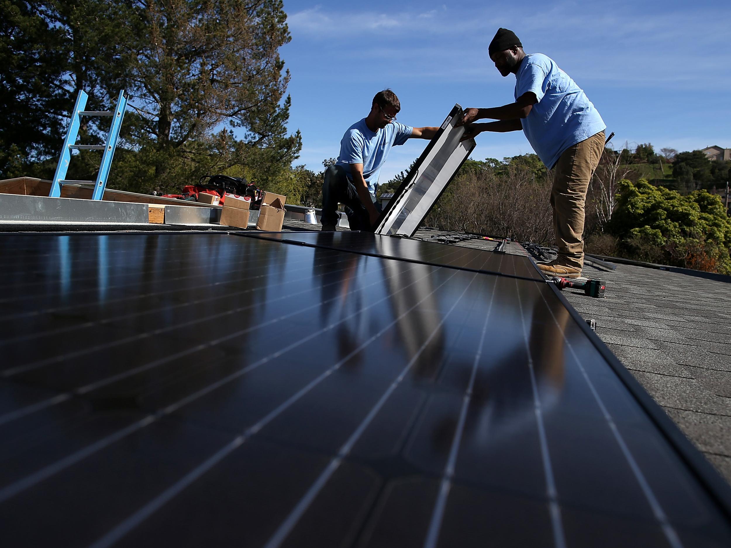 Workers install solar panels on the roof of a home in San Rafael, California