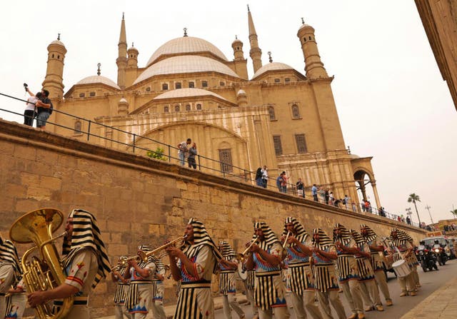 Egyptians dressed in costumes walk past the Cairo Citadel during a ceremony for the transportation of Tutankhamun's chariot