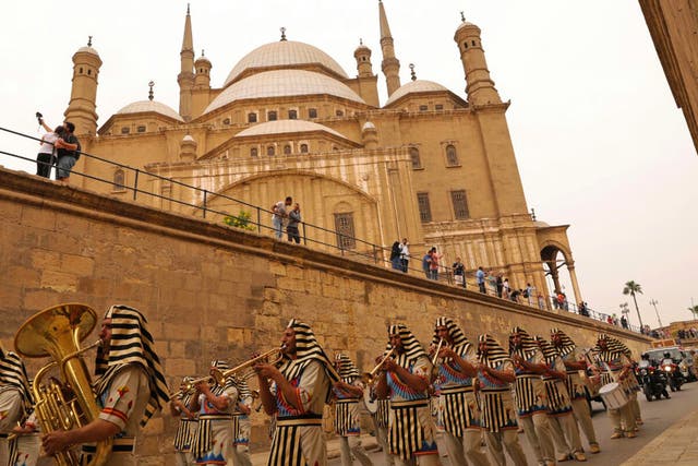 Egyptians dressed in costumes walk past the Cairo Citadel during a ceremony for the transportation of Tutankhamun's chariot