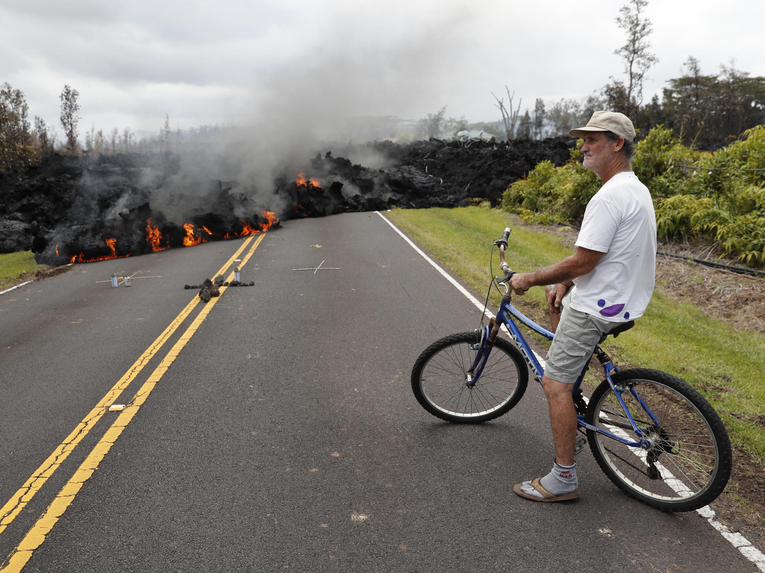 Leilani Estates resident Sam Knox watches the lava stretch across the road just a few hundred yards from his home (AP Photo/Marco Garcia)