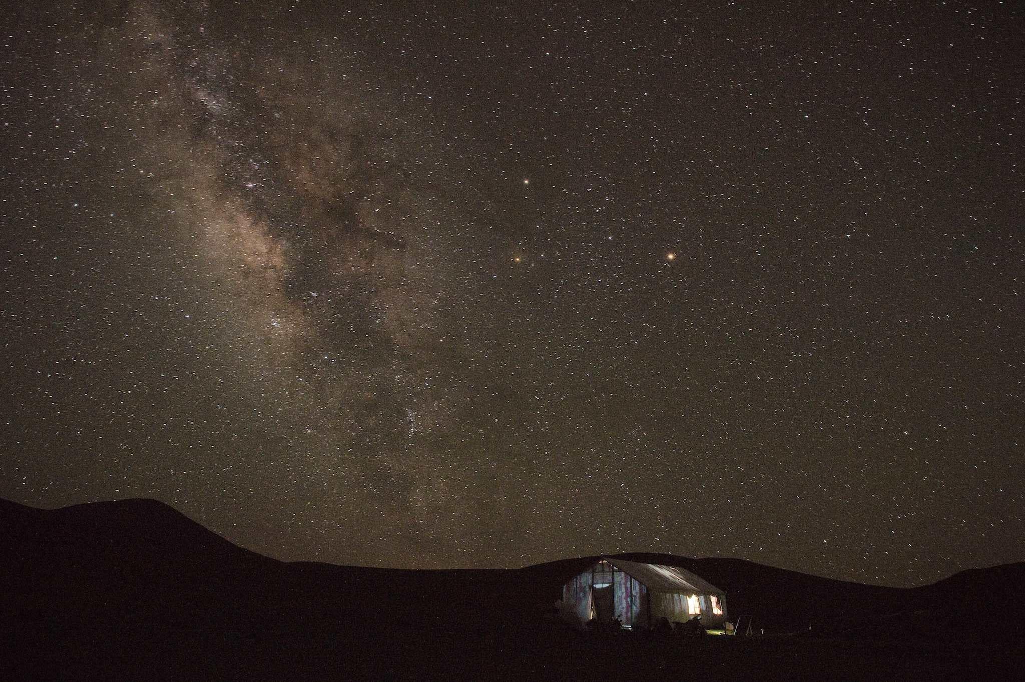 In this picture taken on July 27, 2016, a Tibetan nomad herders tent (bottom R) rests in Yushu county in the mountains of Qinghai province as the Milkyway rises in the night sky
