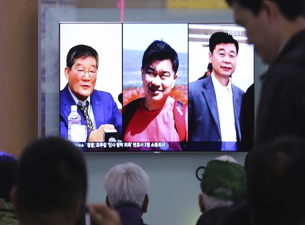 People watch a TV news report on screen, showing portraits of three Americans, Kim Dong Chul, left, Tony Kim and Kim Hak Song, right