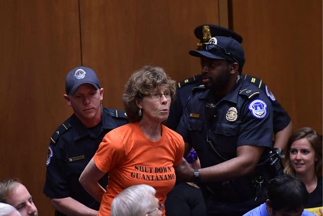 One of the protesters is pictured being led out of the hearing by Capitol Police