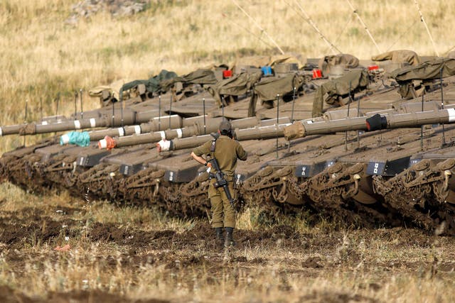An Israeli soldier stands next to Merkava Mark IV tanks in a deployment area near the Syrian border in the Israel-annexed Golan Heights